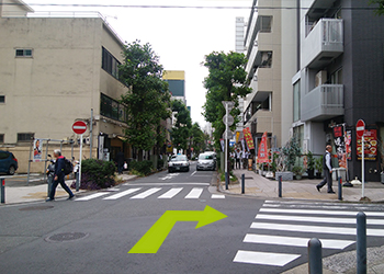 前方左側にパーキングエリア、右手に灰色の建物がある十字路を右に曲がります。