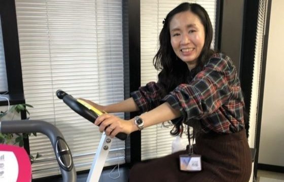 バイクマシンに乗って運動をするスタッフN氏