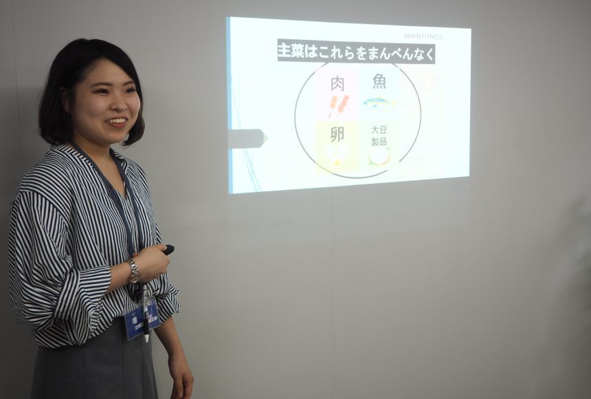 スクリーンの前に立ち説明を行う女性スタッフ